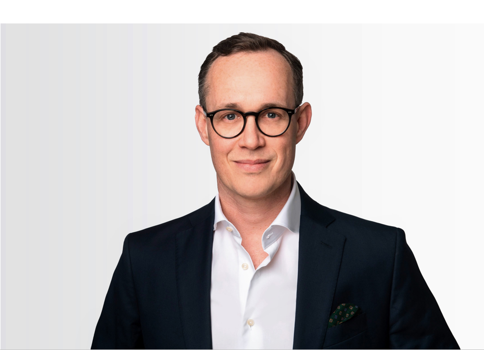 Max Heidbrink trägt einen dunklen Anzug und ein weißes Hemd.
