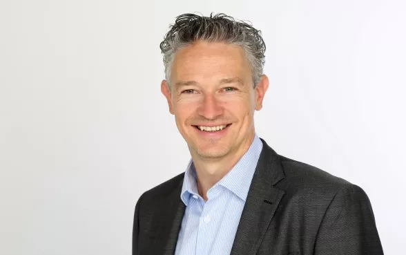 Roman Potyka trägt einem dunklen Sakko mit hellblauem Hemd.