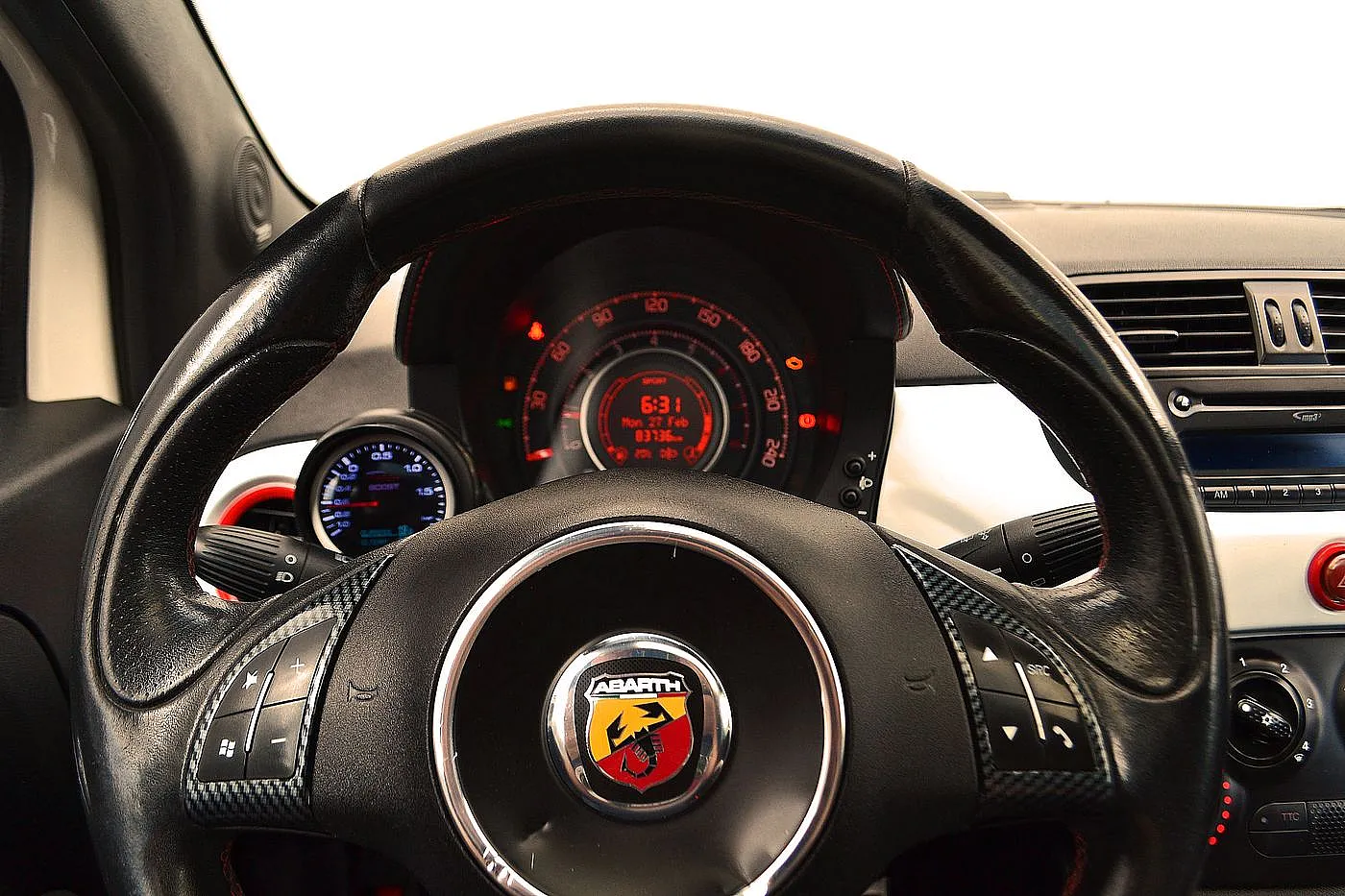 Das schwarze Leder Lenkrad des Fiat Abarth 500 mit Tachoanzeige, Blinkerhebel und Abarth Markenlogo.