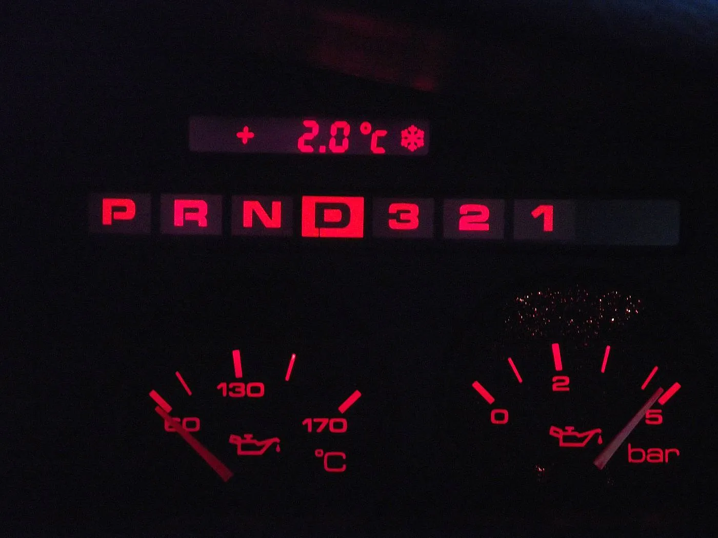 Nahaufnahme von einem rot-erleuchteten Audi v8 Tacho bei Nacht.