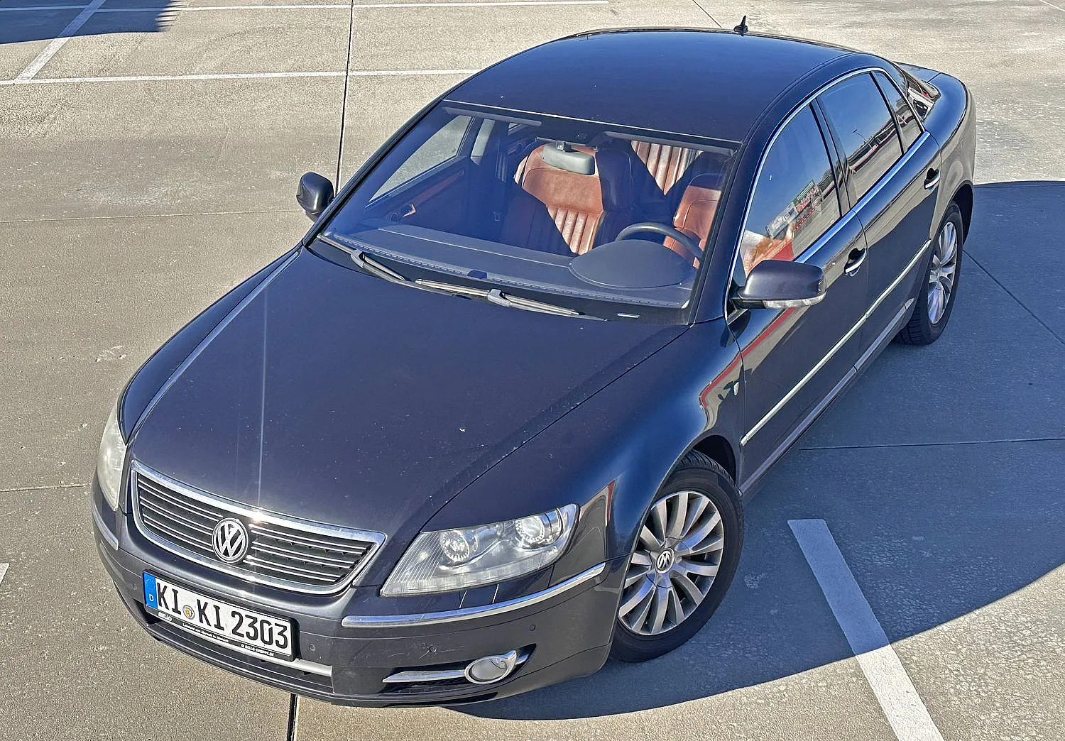 Schwarzer Volkswagen Phaeton Individual mit braunen Ledersitzen parkt auf einem sonnenbeschienen Parkplatz