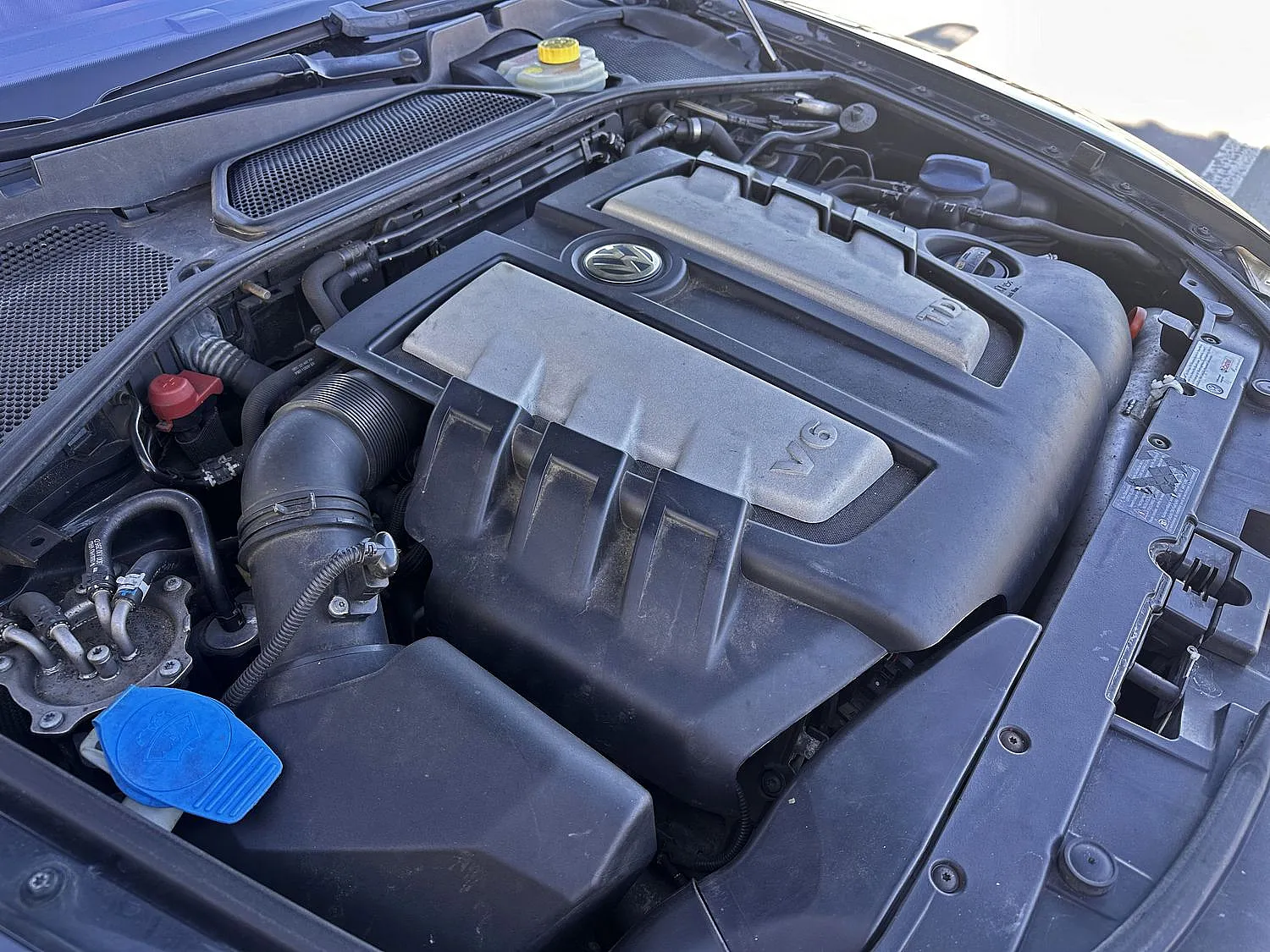 Nahaufnahme des Motorraums eines Fahrzeugs mit Schwerpunkt auf einem V6-TDI-Motor. Der Bereich scheint gut gepflegt zu sein, mit sichtbaren Komponenten, Schläuchen und Abdeckungen.