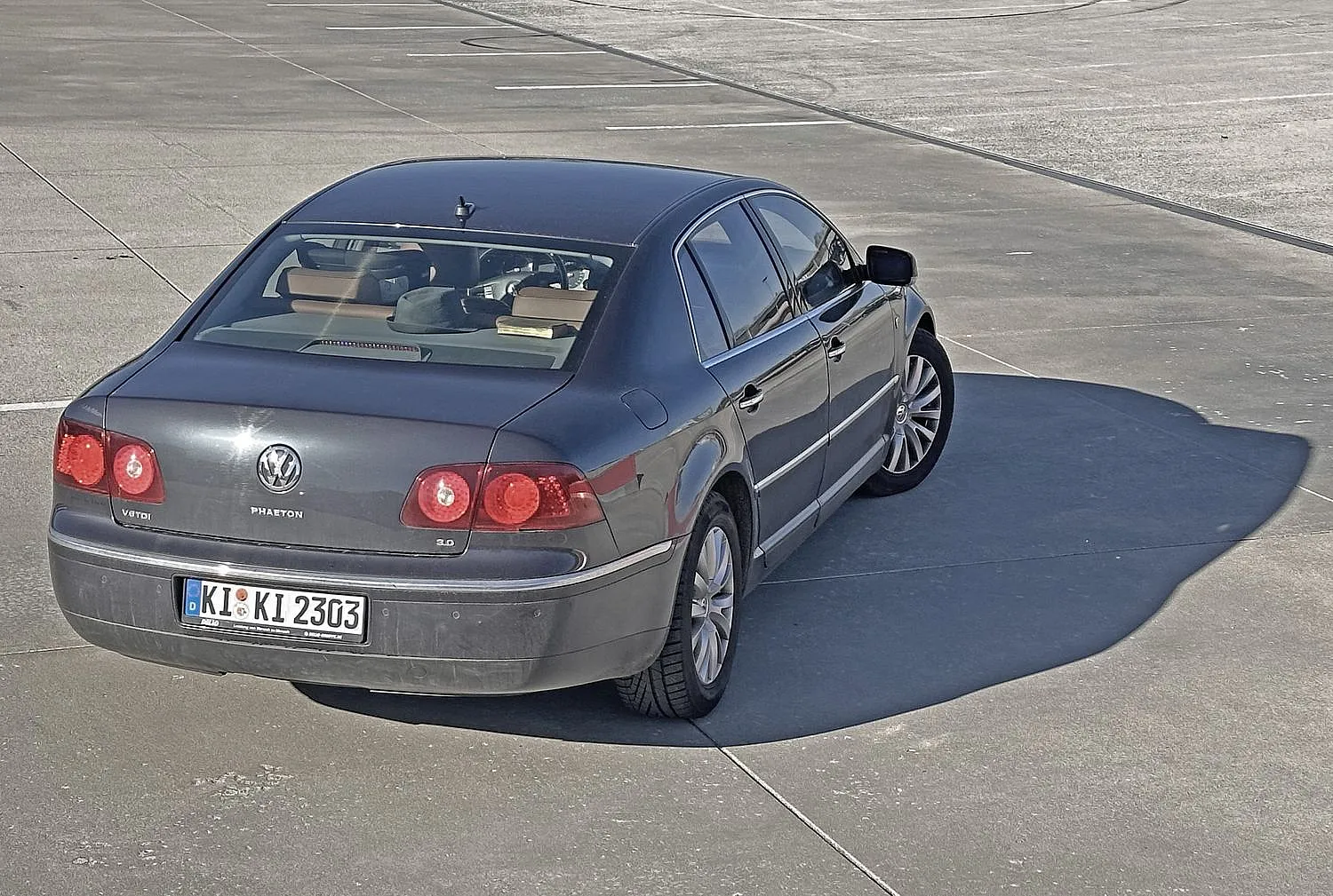 Rückansicht eines grauen Volkswagen Phaeton V6 TDI an einem sonnigen Tag, mit roten Rückleuchten und einem deutschen Nummernschild, geparkt auf Asphalt.