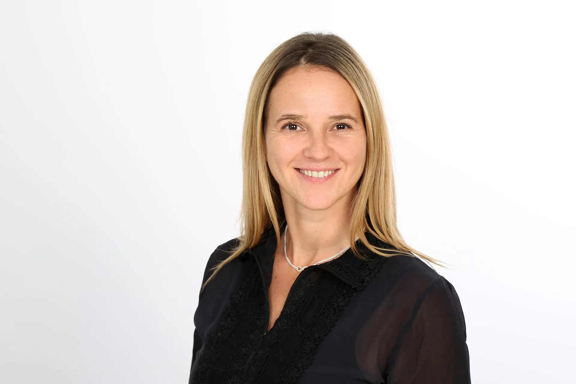 Daniela Zierold, Head of Marketing, Brand Management und Communications bei Hiscox, lächelt in die Kamera. Sie trägt eine schwarze Bluse, eine Halskette und hat blonde Haare.