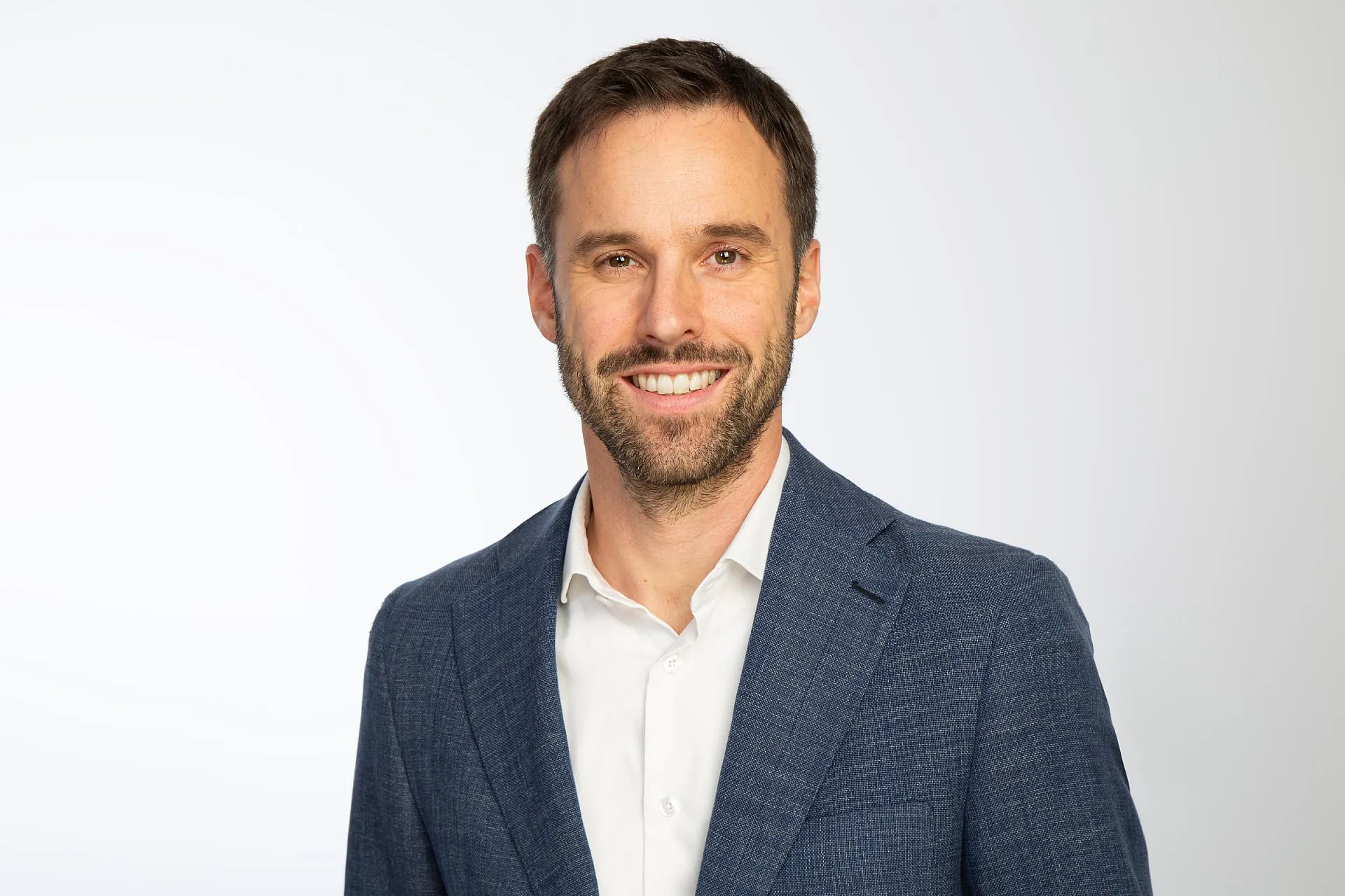 Franz Kupfer ist Product Head Professional Indemnity, D&O bei Hiscox Sa. Er trägt einen dunkelblauen Anzug mit weißem Hemd drunter.