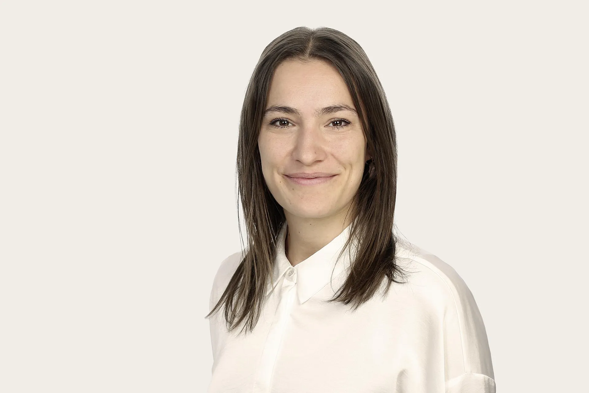 Lisa Lücke, eine Frau mit schulterlangem braunem Haar, trägt ein weißes Hemd.