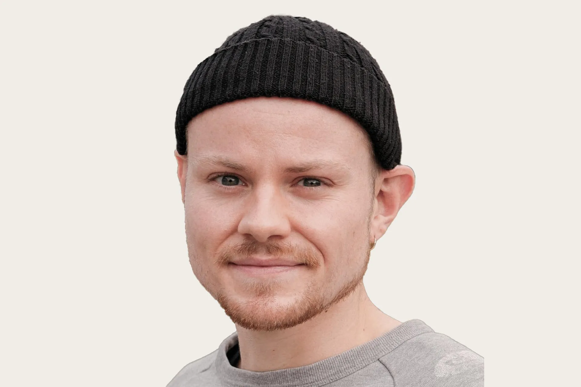 Nick Oestreich, ein Gastautor bei Hiscox, trägt eine schwarze Strickmütze und ein graues Shirt.