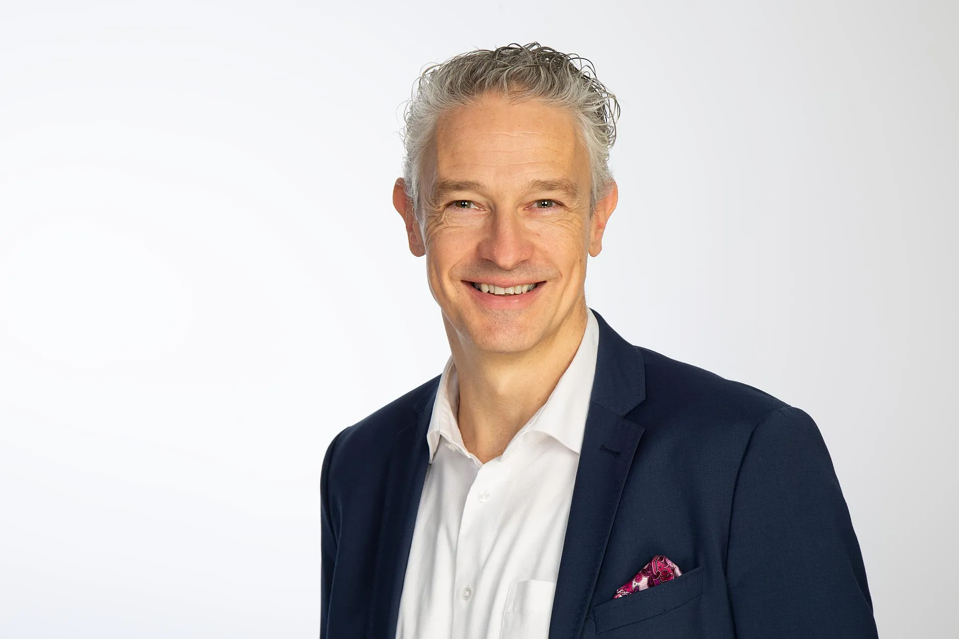 Auf dem Bild ist Roman Potyka zu sehen, Head of Product & Underwriting bei Hiscox Deutschland, ein grauhaariger Mann im Jackett, der in die Kamera lächelt.