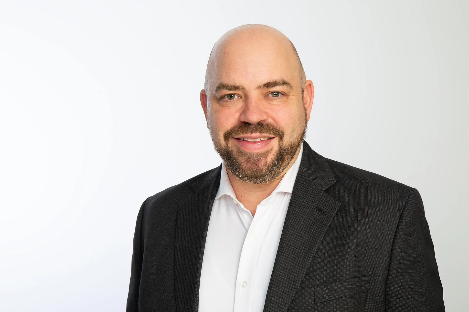 Tobias Wenhart von Hiscox trägt einen Anzug und Hemd vor weißem Hintergrund.