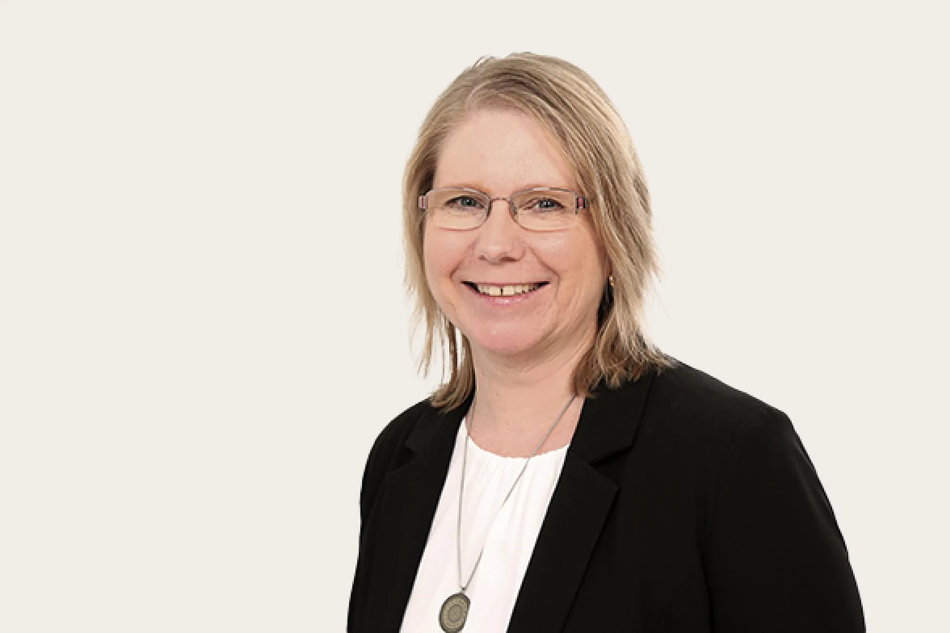 Regina Huber, eine Frau mit schulterlangem Haar, trägt einem schwarzem Blazer und weißem Oberteil.