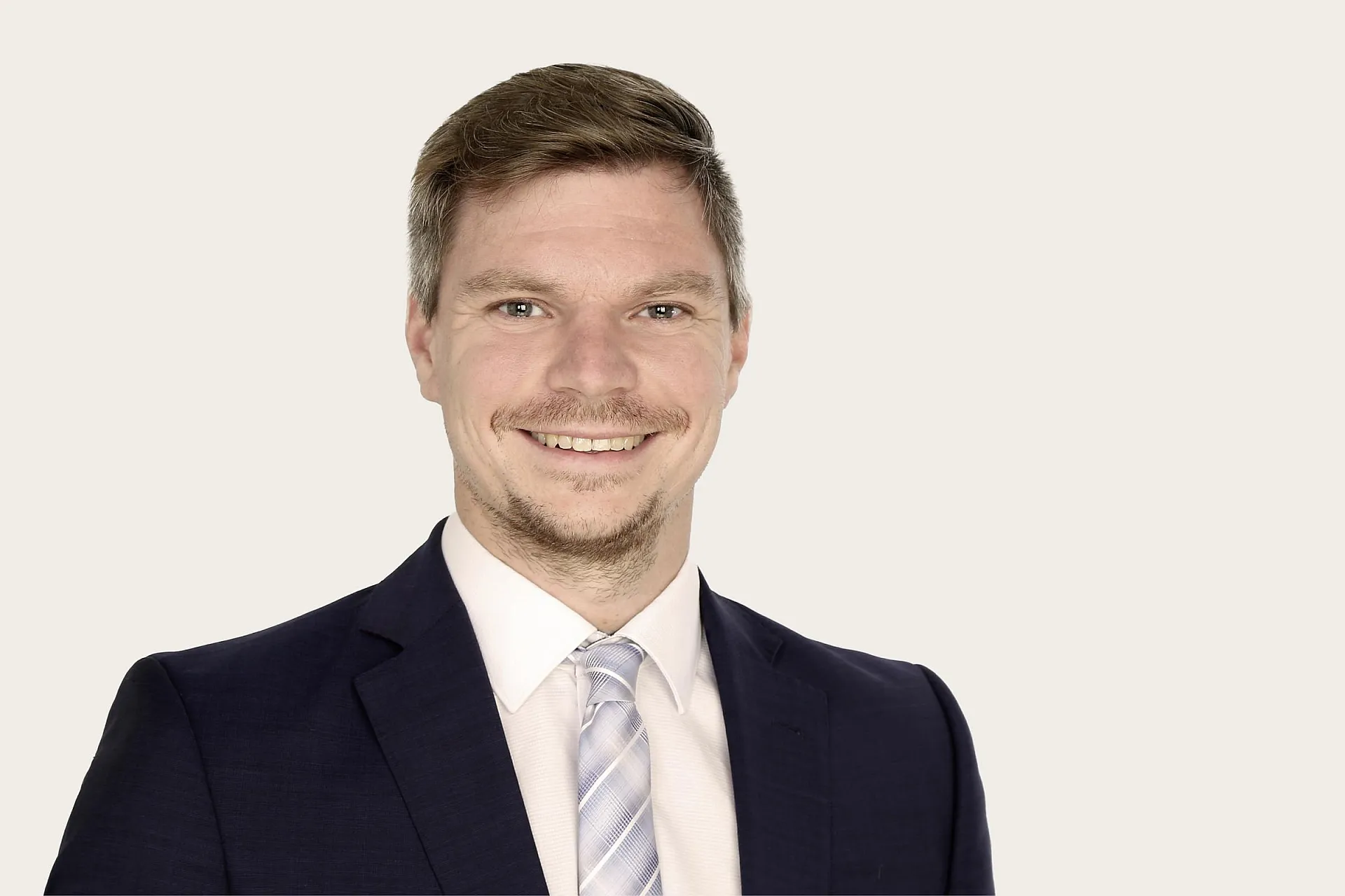 Hiscox Experte Tobias Knoll lächelnd im Anzug und Krawatte.