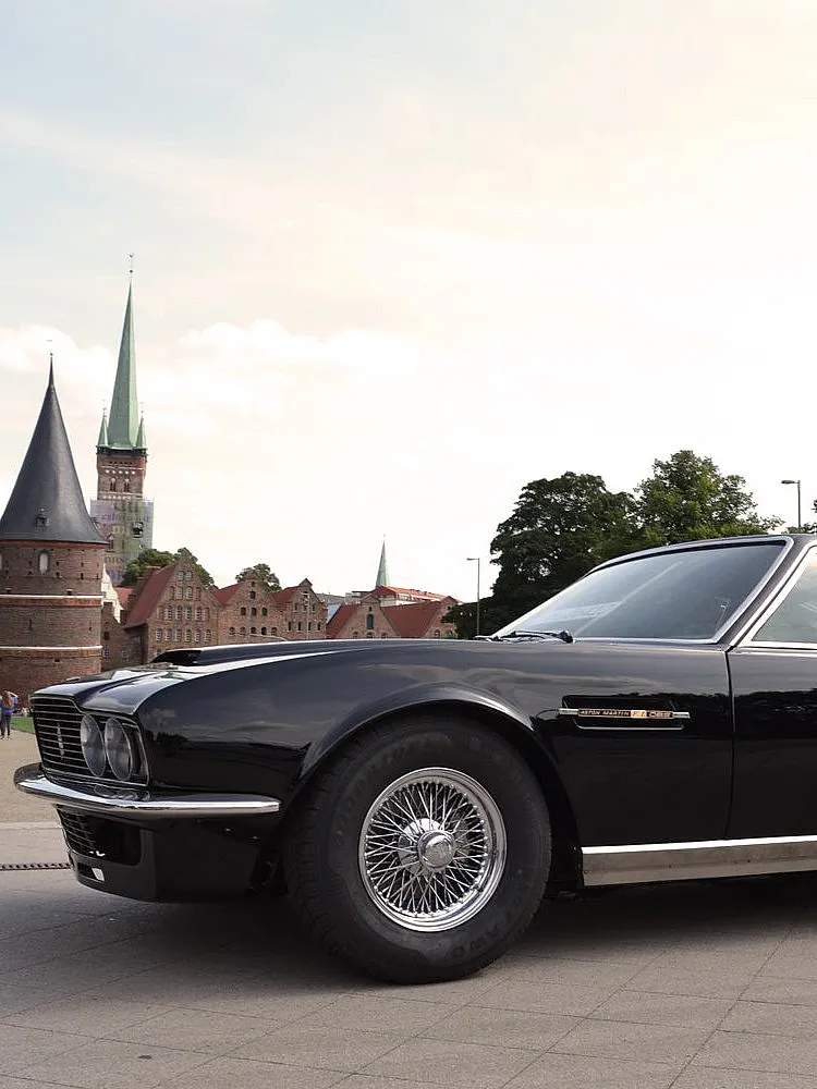 Schwarzer Aston Martin vor dem historischen Holstentor in Lübeck, Deutschland