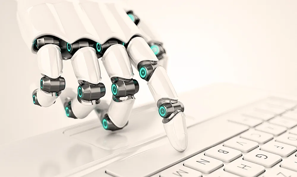 Eine weißt Roboterhand tippt auf die Leertaste einer weißen Tastatur