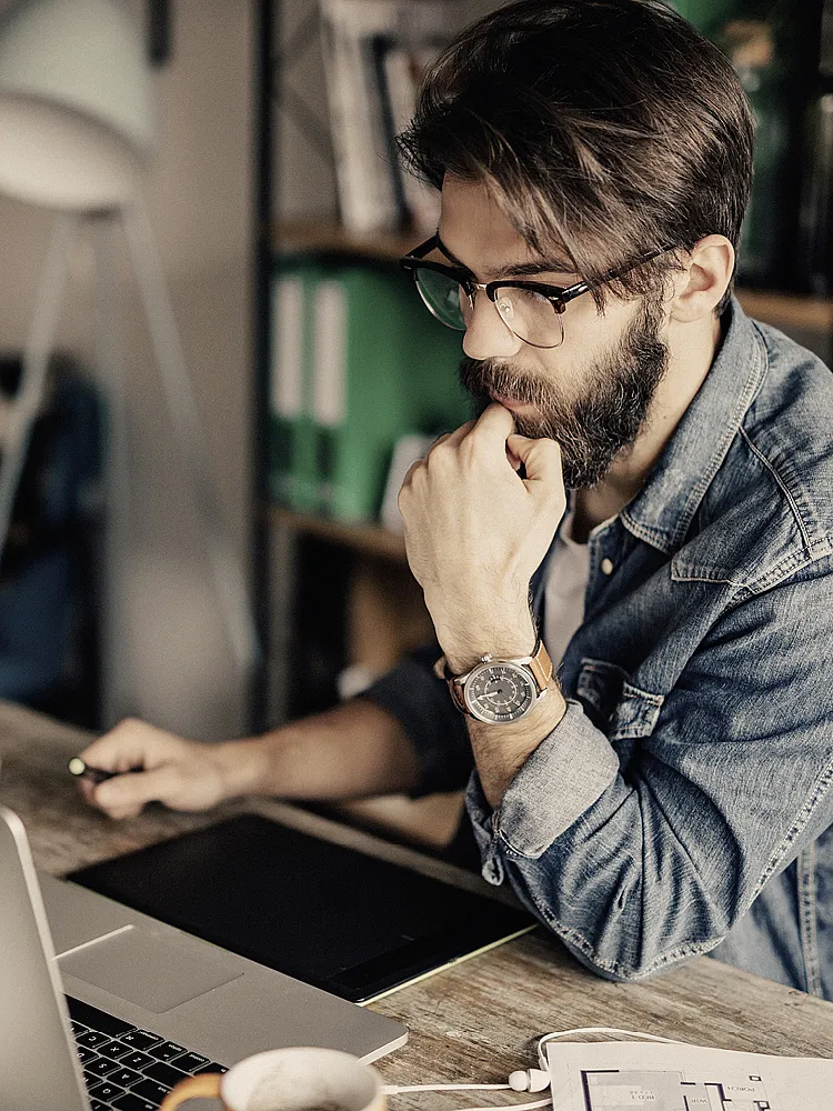 Ein junger Mann in Jeanshemd arbeitet an seinem Laptop