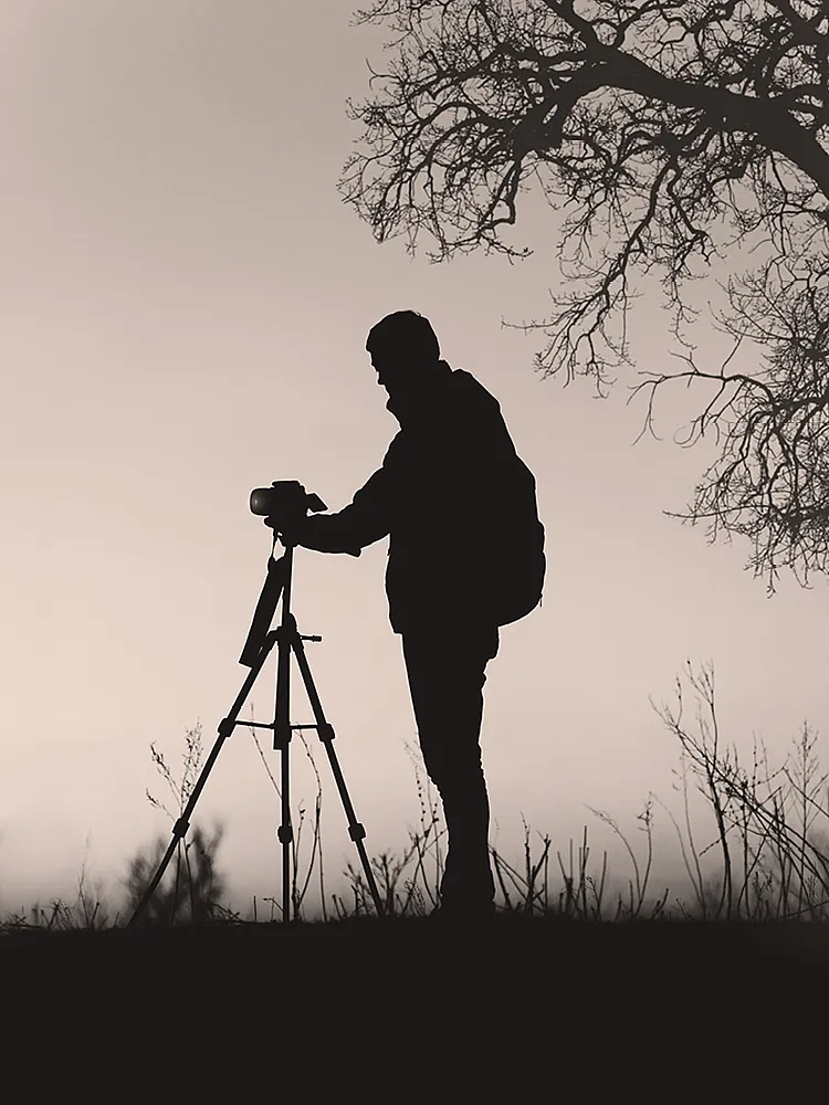 Ein Fotograf richtet seine Kamera auf einem Stativ in der Natur aus