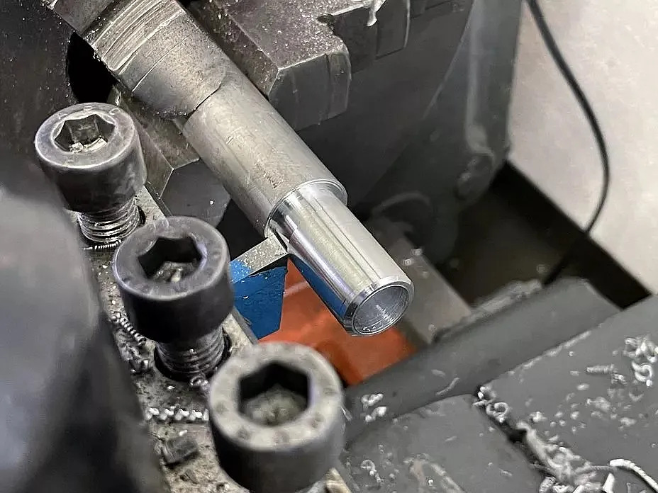 Nahaufnahme einer Drehmaschine, die ein zylindrisches Metallwerkstück bearbeitet.