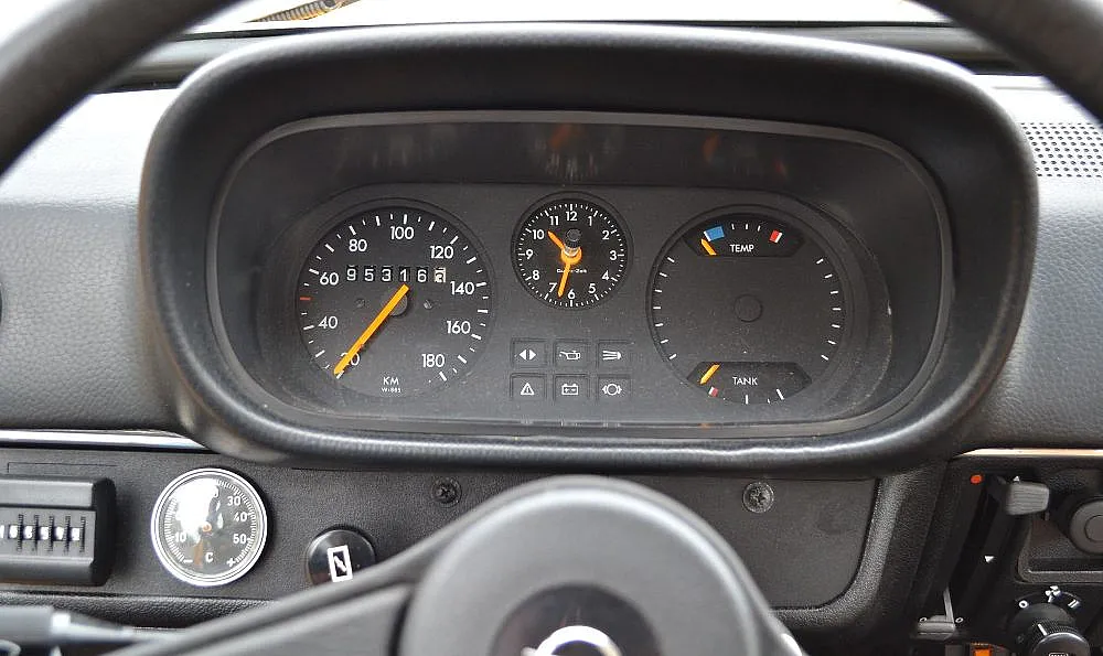 Armaturenbrett eines Autos mit Tachometer, Drehzahlmesser, Kraftstoffanzeige, Motortemperaturanzeige und einer analogen Uhr.
