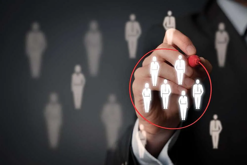 Zielgruppenanalyse: Hand zeichnet roten Kreis um ausgewählte Figuren als Symbol für Zielgruppenfokussierung.