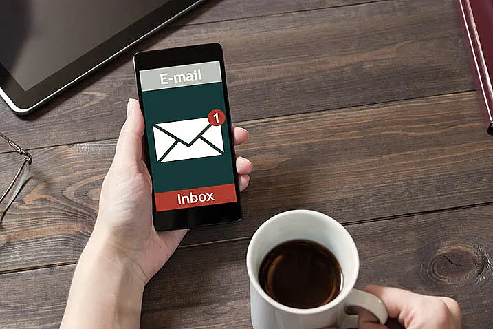 E-Mail-Benachrichtigung auf Smartphone: Person hält Smartphone und Kaffeetasse in der Hand