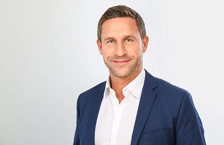 stefan sievers trägt ein weißes Hemd und ein blaues Sakko.