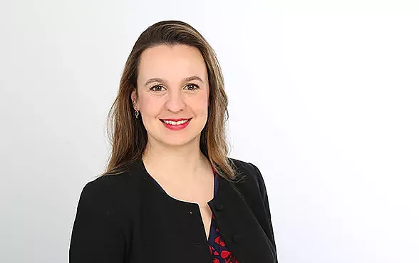 Alina Sucker mit rotem Lippenstift und schwarzer Blazer bei der Arbeit für Hiscox.