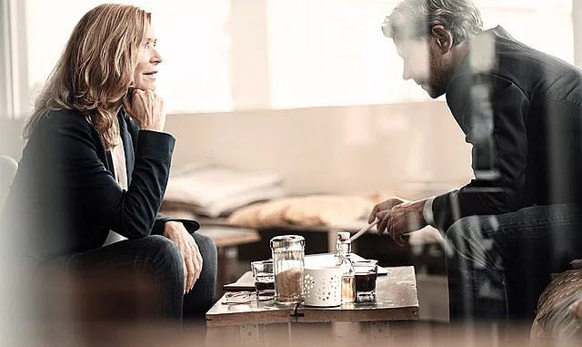 Ein Mann und eine Frau sitzen an einem Sofatisch und unterhalten sich