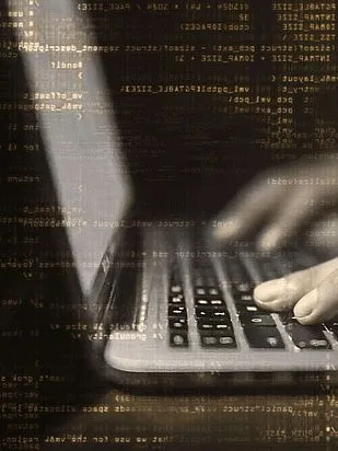 Die Hände einer Person tippen auf einem Laptop. Das Bild ist braun-gräulich gefärbt.