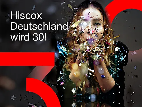 Eine Frau pustet golden glänzende Schnipsel von ihren Händen. Das Bild zeigt außerdem den Schriftzug "Hiscox Deutschland wird 30!" sowie eine große rote 3 und eine 0 jeweils links unten und rechts oben in der Bildecke