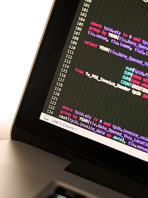 Fotografie eines Laptopbildschirms mit sichtbarem SQL-Code in farbiger Syntaxhervorhebung, der Datenabfragen und Gruppierungen nach Jahr und Datum zeigt. Der Code enthält Schlüsselwörter wie "select", "from" und "where" sowie Funktionen zur Summierung und Datumsformatierung, erkennbar an Zeilennummern am linken Rand.