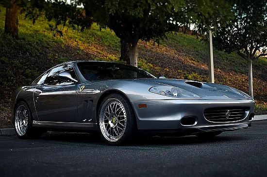 Ferrari 550 Maranello in silber vor Park-Hintergrund in schräger Frontansicht