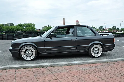 BMW 3er E30 Oldtimer in Dunkelgrau auf einem Parkplatz in Deutschland, klassischer Youngtimer mit typischen Felgen