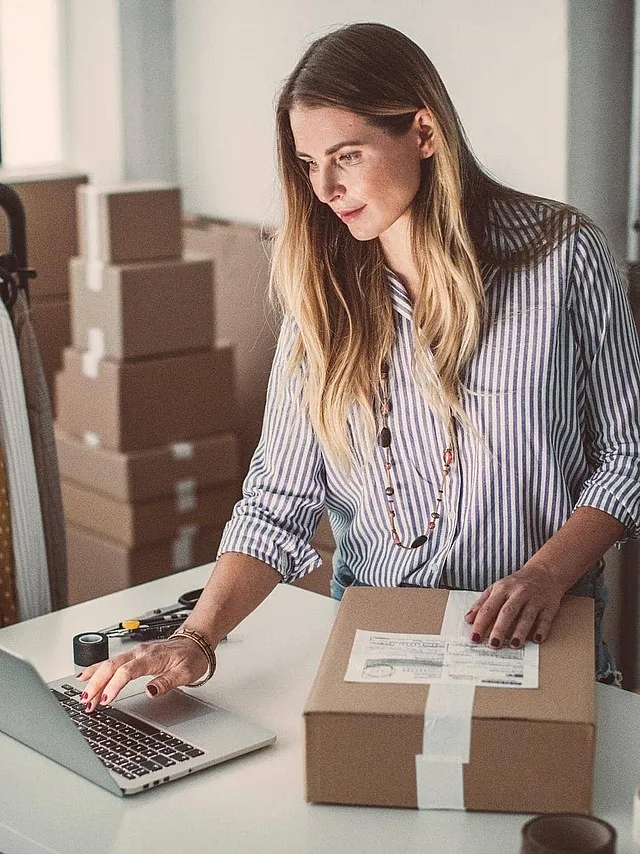 Onlineshop-Versicherung von Hiscox: Onlineshop-Betreiberin arbeitet in ihrem Warenlager am Laptop