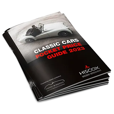 Gestapelte Booklets mit dem Titel ‚CLASSIC CARS POCKET PRICE GUIDE 2023‘ und einem weißen Cabrio auf dem Cover, gebrandet mit dem HISCOX-Logo.