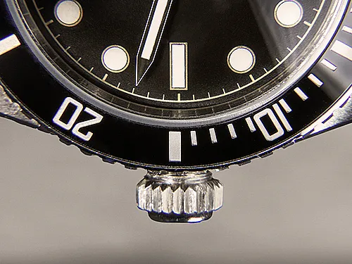 Nahaufnahme einer Armbanduhr mit Fokus auf Lünette und Krone; Markierungen für 10 und 20 Minuten sichtbar.
