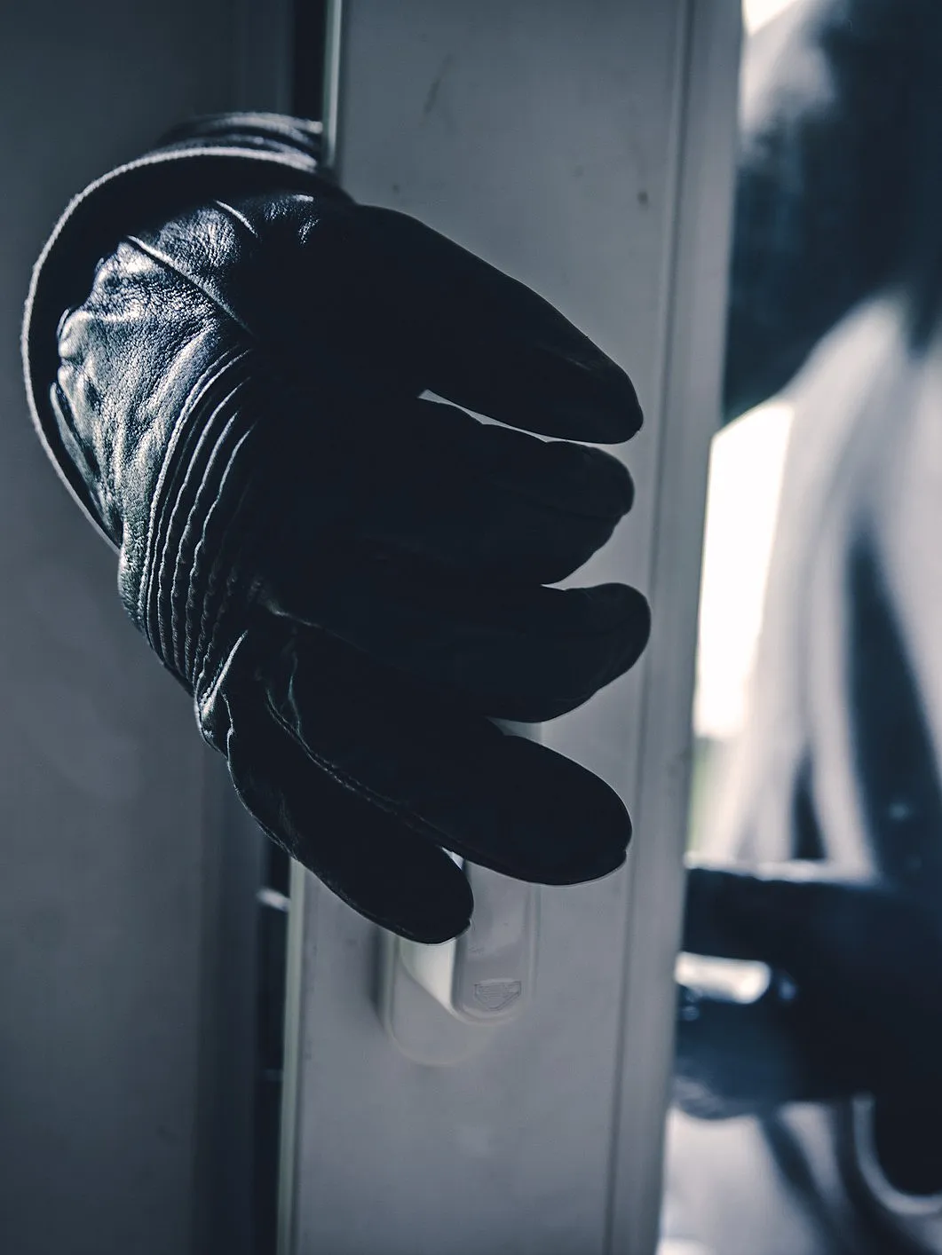 Einbruch: Kriminelle Person mit Handschuhen versucht, eine Tür aufzuhebeln